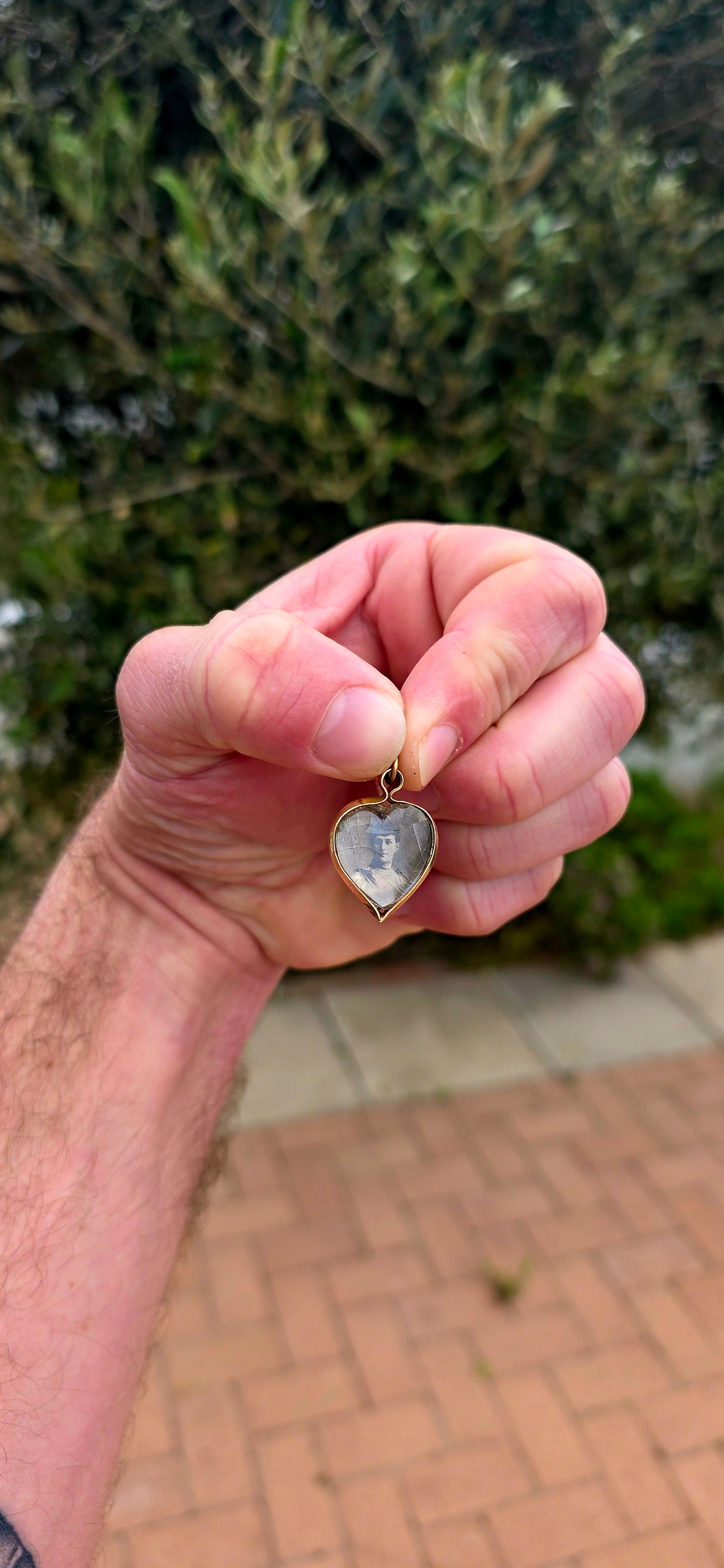 This antique Edwardian-era heart-shaped fob pendant features miniature photographic portraits of King Edward VII and Queen Alexandra, one displayed on either side beneath protective glass.