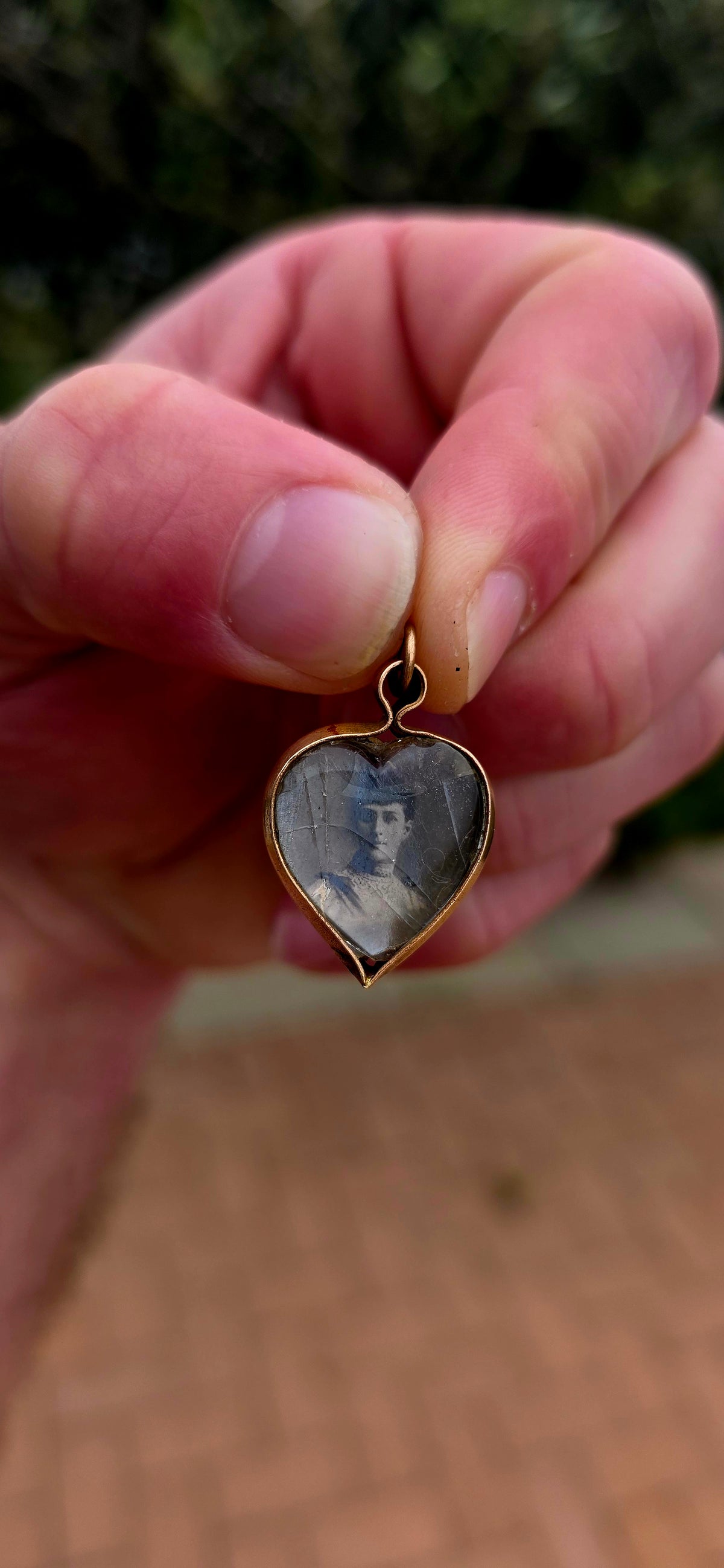 This antique Edwardian-era heart-shaped fob pendant features miniature photographic portraits of King Edward VII and Queen Alexandra, one displayed on either side beneath protective glass.