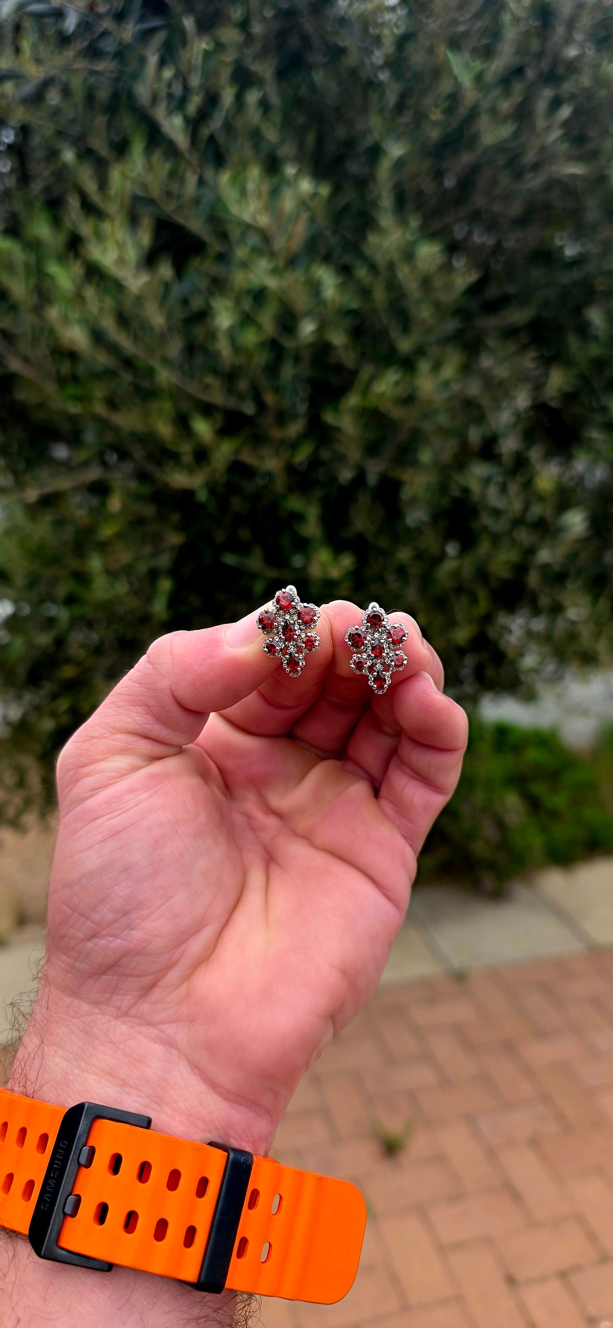 A wonderfully feminine pair of sterling silver earrings designed in the shape of delicate orchid flowers, absolutely bursting with rich garnet red and sparkle.