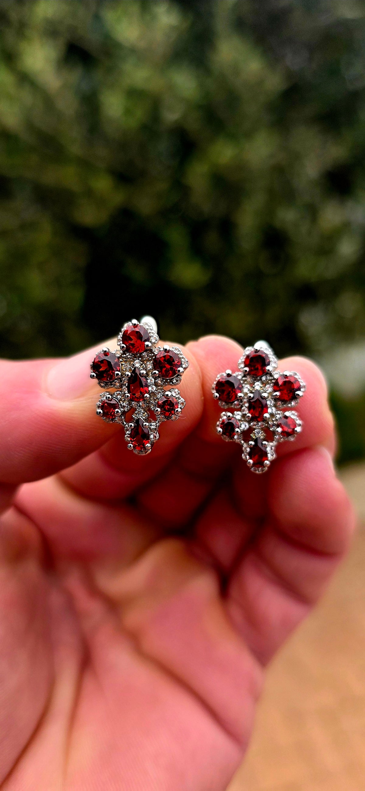 A wonderfully feminine pair of sterling silver earrings designed in the shape of delicate orchid flowers, absolutely bursting with rich garnet red and sparkle.