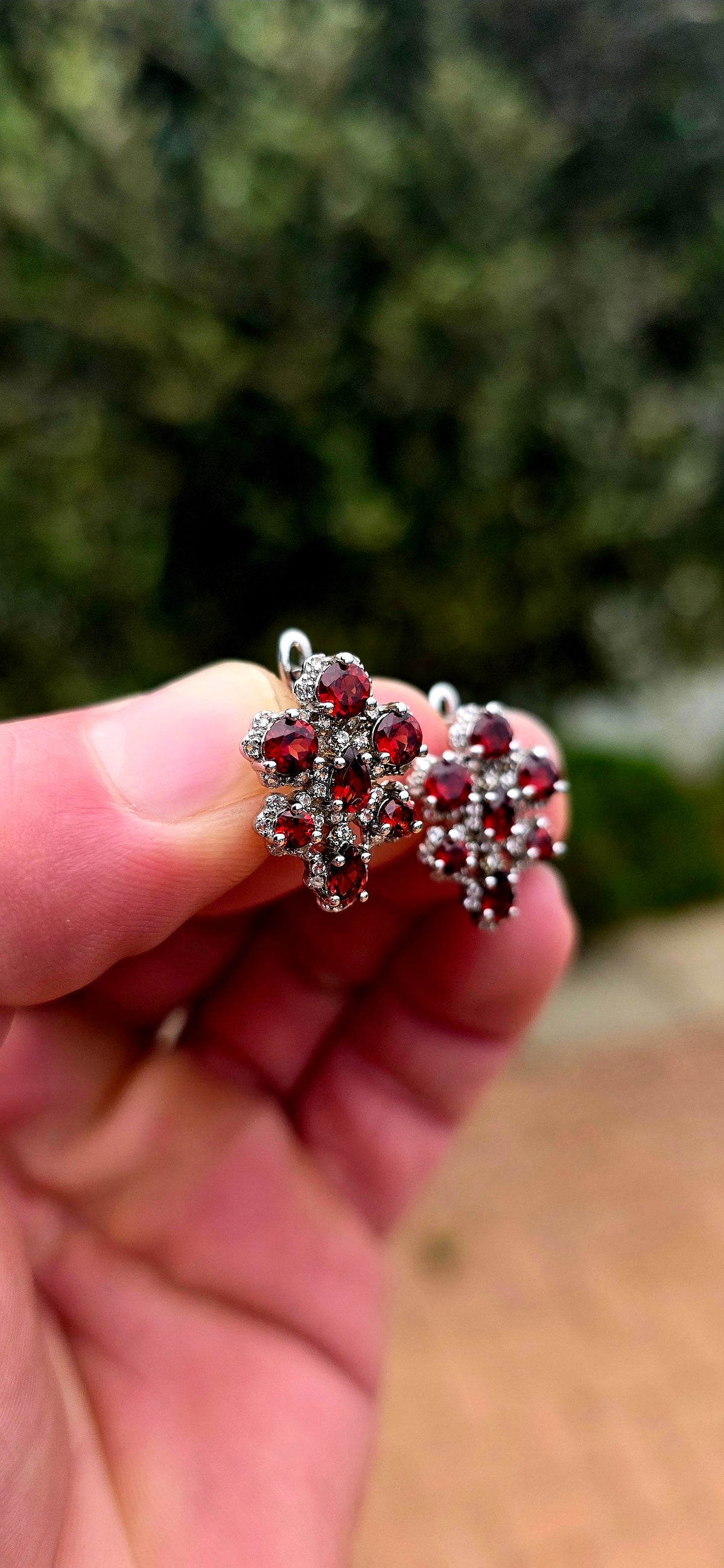 A wonderfully feminine pair of sterling silver earrings designed in the shape of delicate orchid flowers, absolutely bursting with rich garnet red and sparkle.