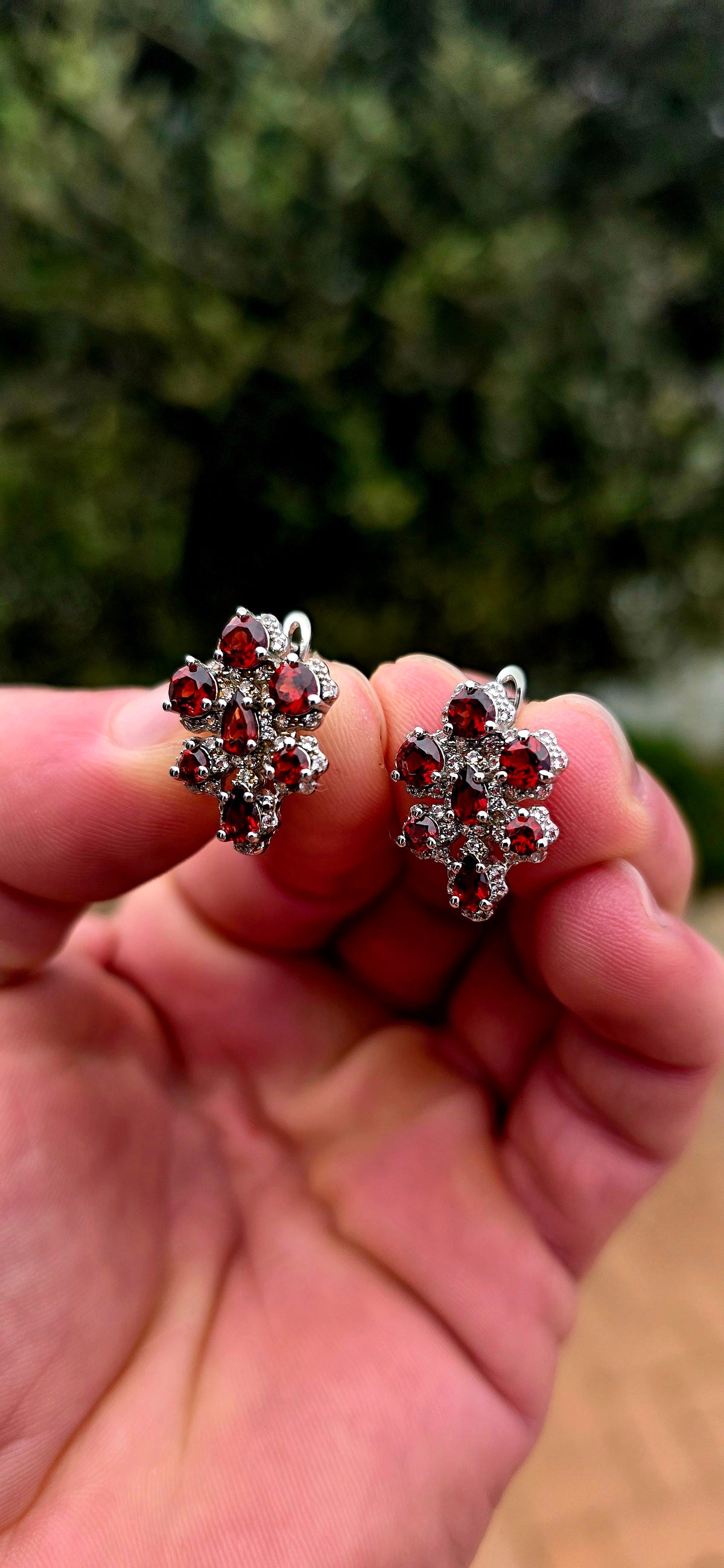 A wonderfully feminine pair of sterling silver earrings designed in the shape of delicate orchid flowers, absolutely bursting with rich garnet red and sparkle.