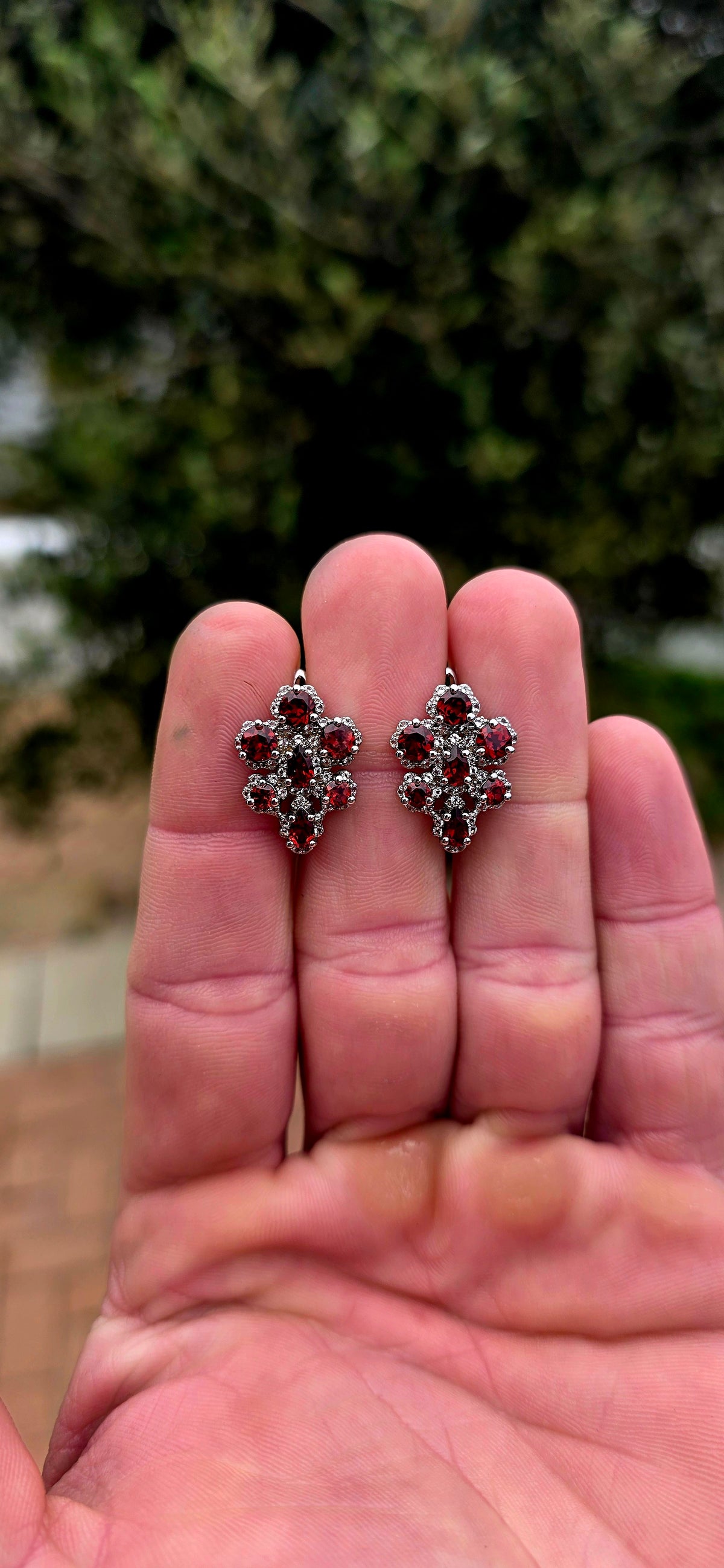 A wonderfully feminine pair of sterling silver earrings designed in the shape of delicate orchid flowers, absolutely bursting with rich garnet red and sparkle.