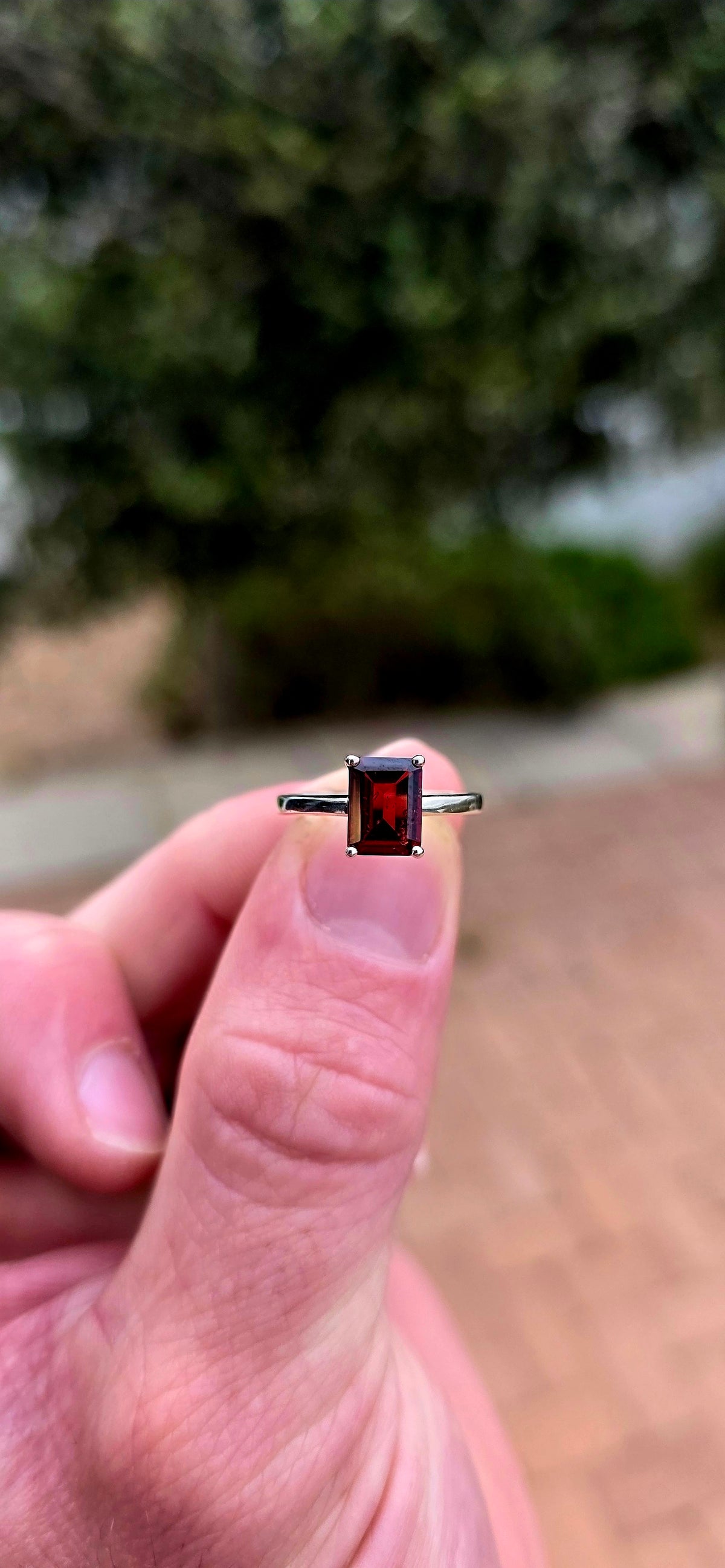 Clean, classical and beautifully elegant! This sterling silver solitaire ring features a gorgeous emerald-cut garnet.