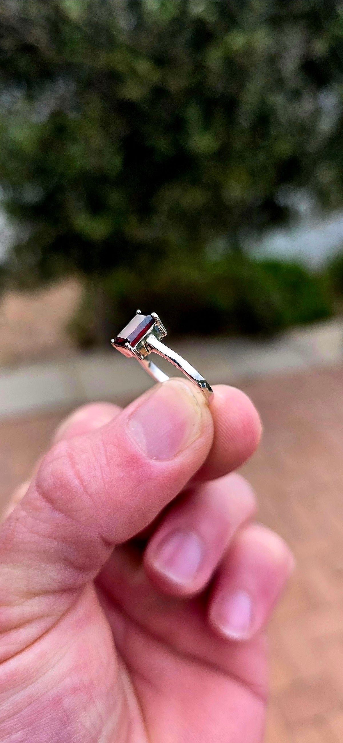 Clean, classical and beautifully elegant! This sterling silver solitaire ring features a gorgeous emerald-cut garnet.