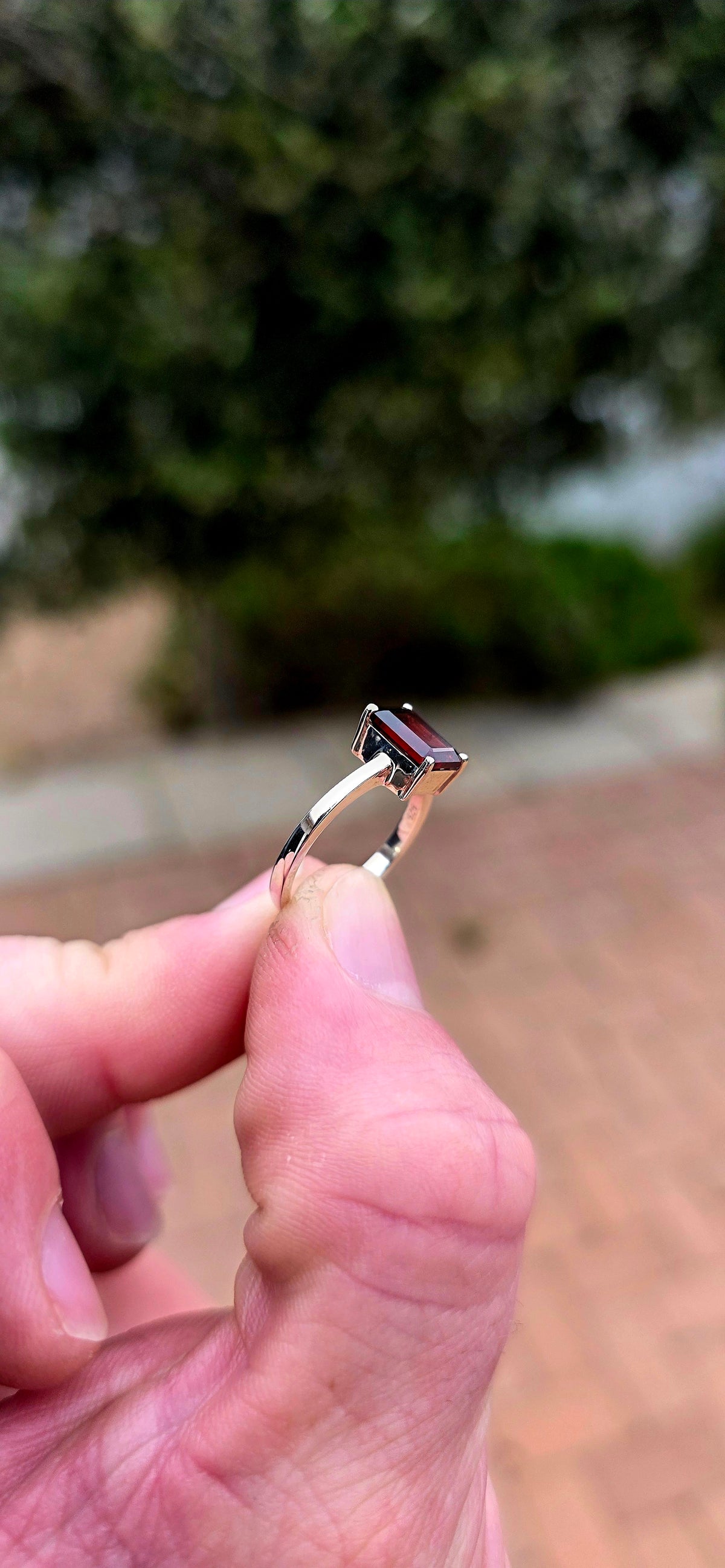 Clean, classical and beautifully elegant! This sterling silver solitaire ring features a gorgeous emerald-cut garnet.