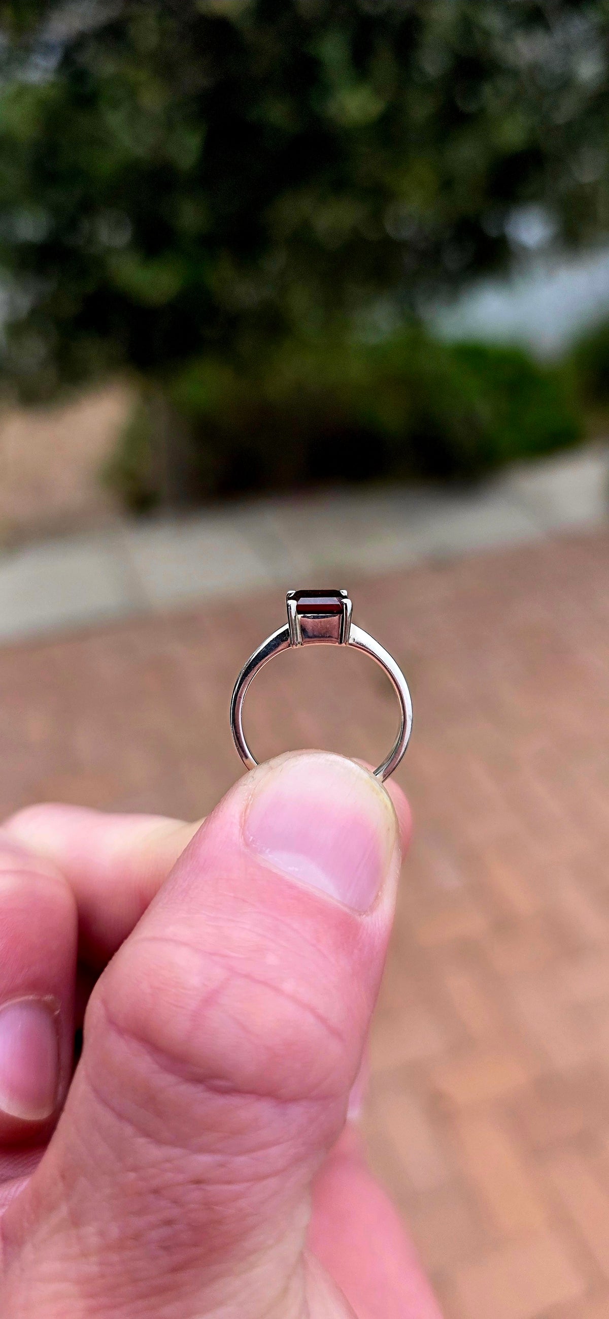 Clean, classical and beautifully elegant! This sterling silver solitaire ring features a gorgeous emerald-cut garnet.