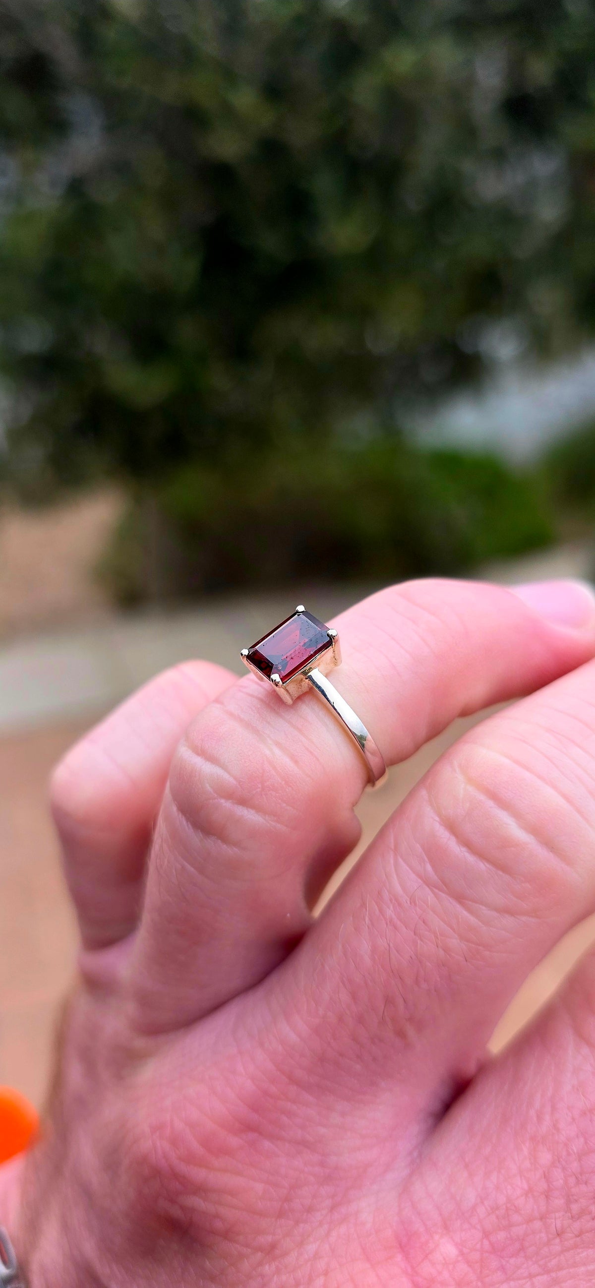 Clean, classical and beautifully elegant! This sterling silver solitaire ring features a gorgeous emerald-cut garnet.