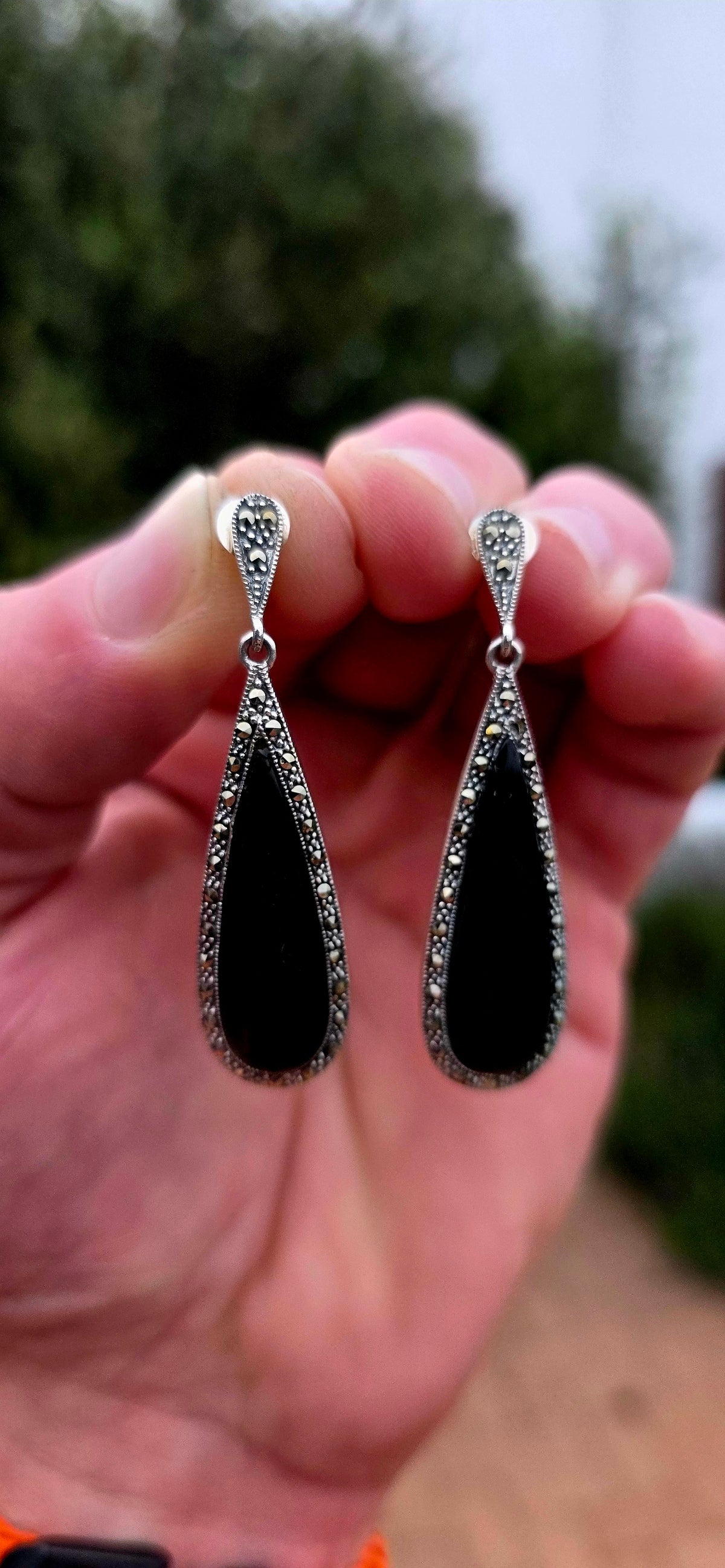 An incredibly elegant pair of Art Deco Revival sterling silver drop earrings, combining dramatic black onyx with the unmistakable sparkle of marcasite.