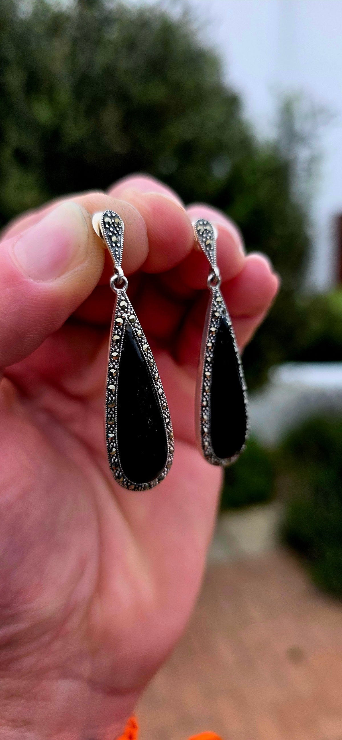 An incredibly elegant pair of Art Deco Revival sterling silver drop earrings, combining dramatic black onyx with the unmistakable sparkle of marcasite.