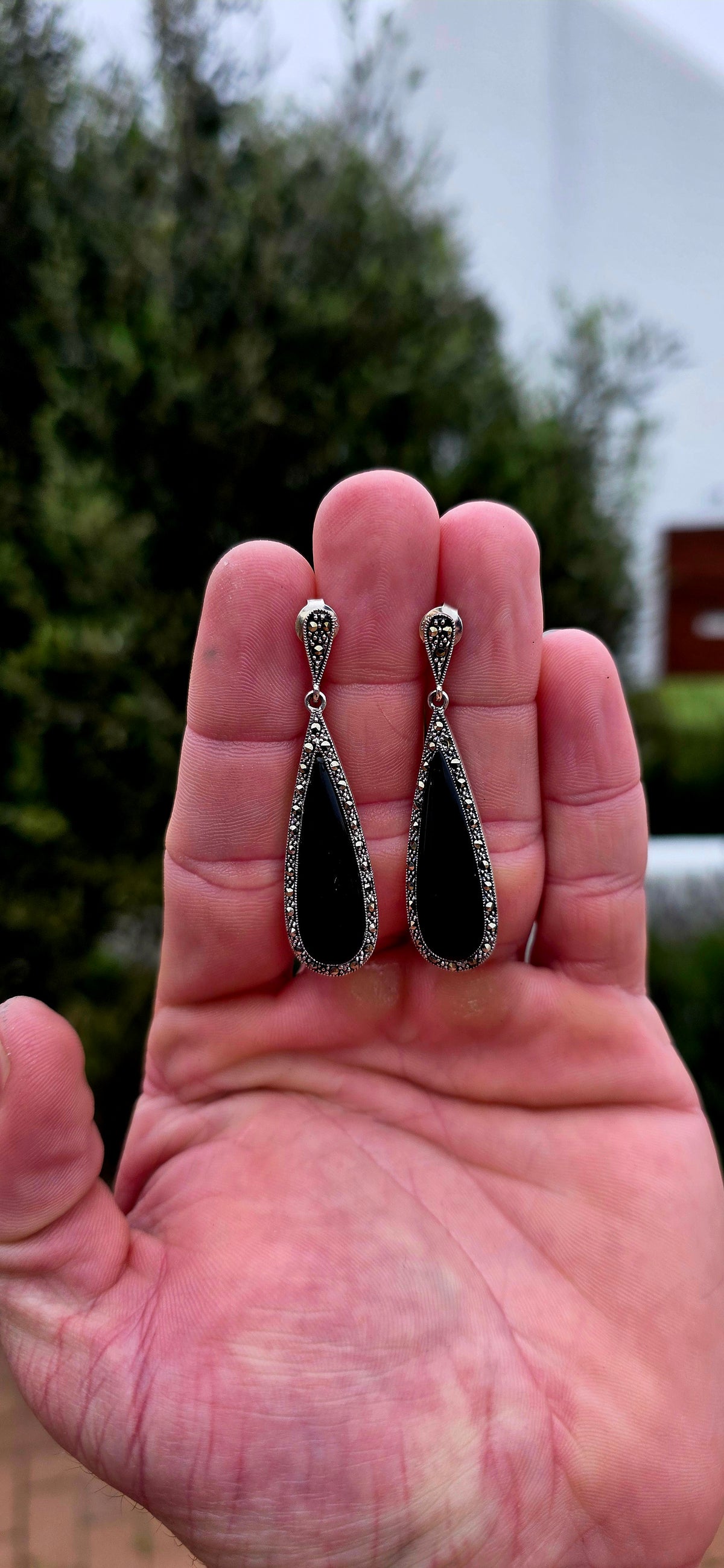 An incredibly elegant pair of Art Deco Revival sterling silver drop earrings, combining dramatic black onyx with the unmistakable sparkle of marcasite.