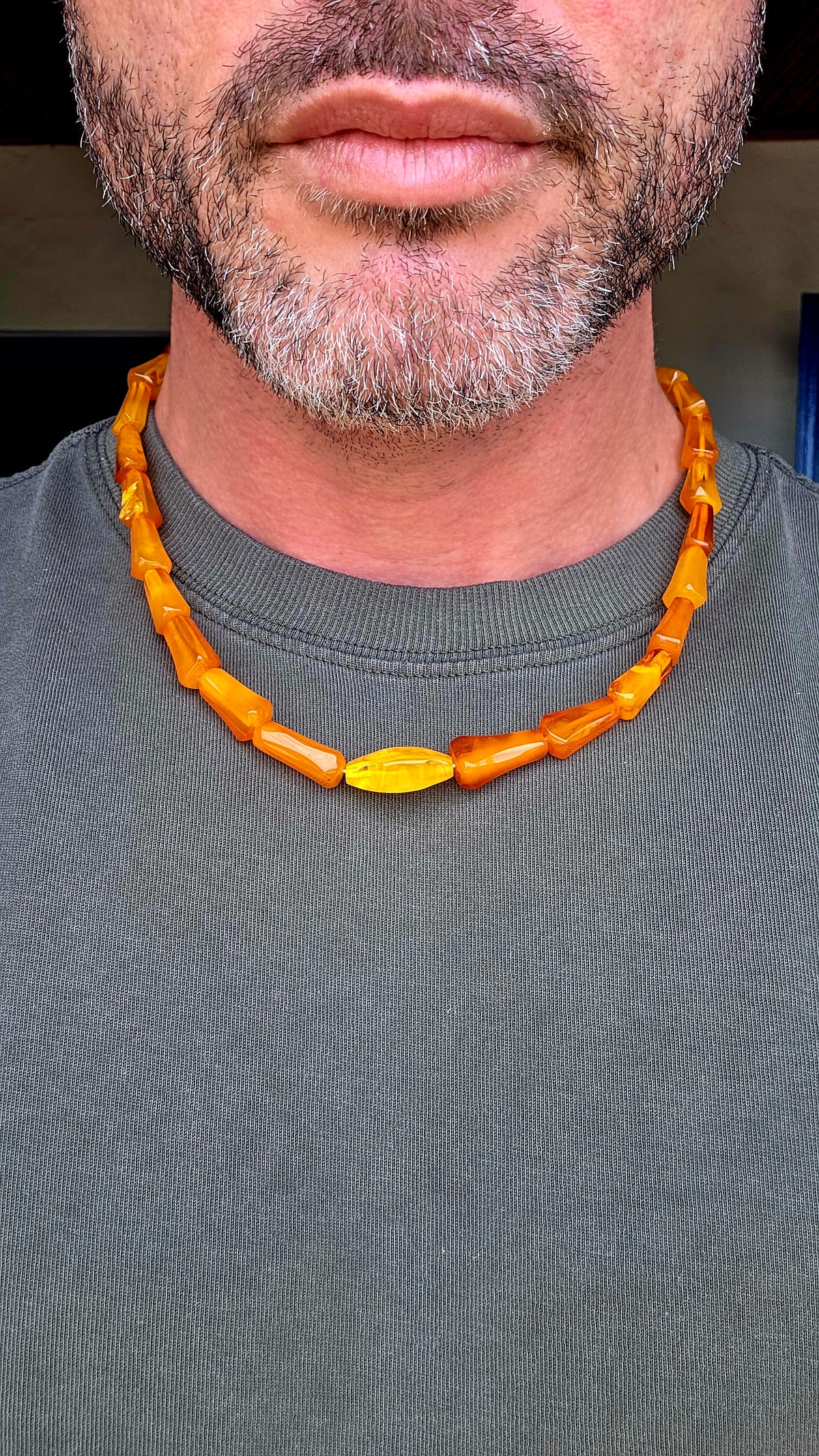 A striking Art Deco era necklace featuring a beautiful arrangement of elongated, graduated barrel-shaped beads in rich golden-orange, warm cognac and creamy butterscotch tones.