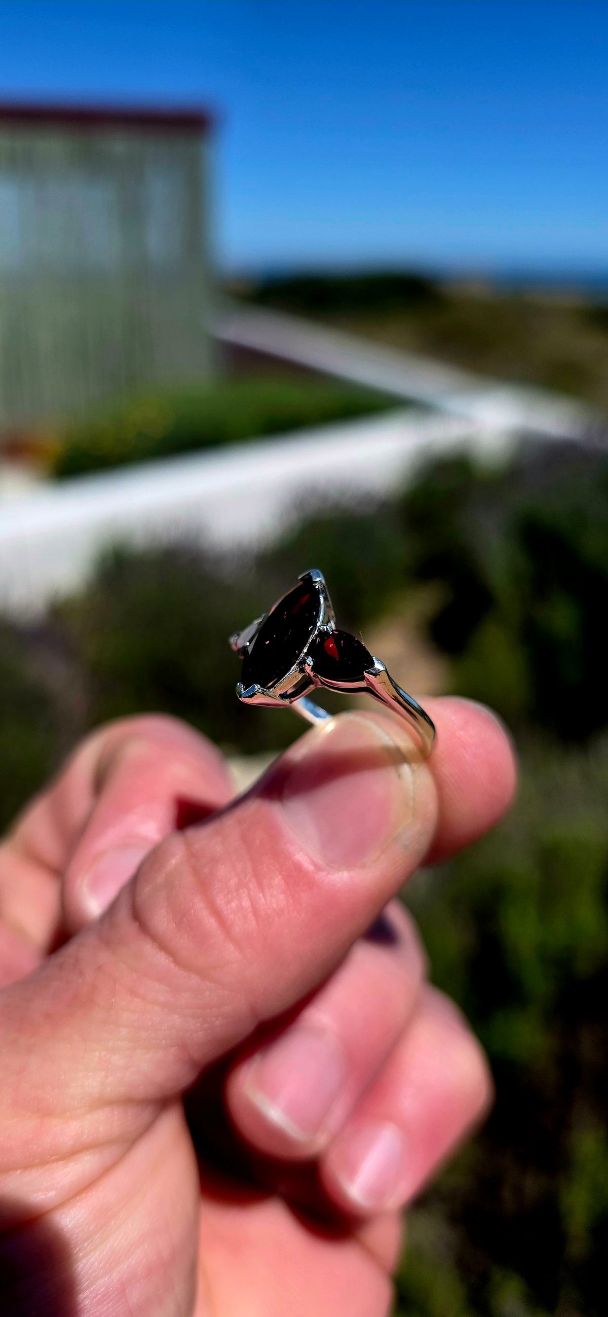A gorgeous sterling silver trilogy ring featuring three beautifully faceted, deep wine-red garnets in a wonderfully elegant and slightly dramatic design!