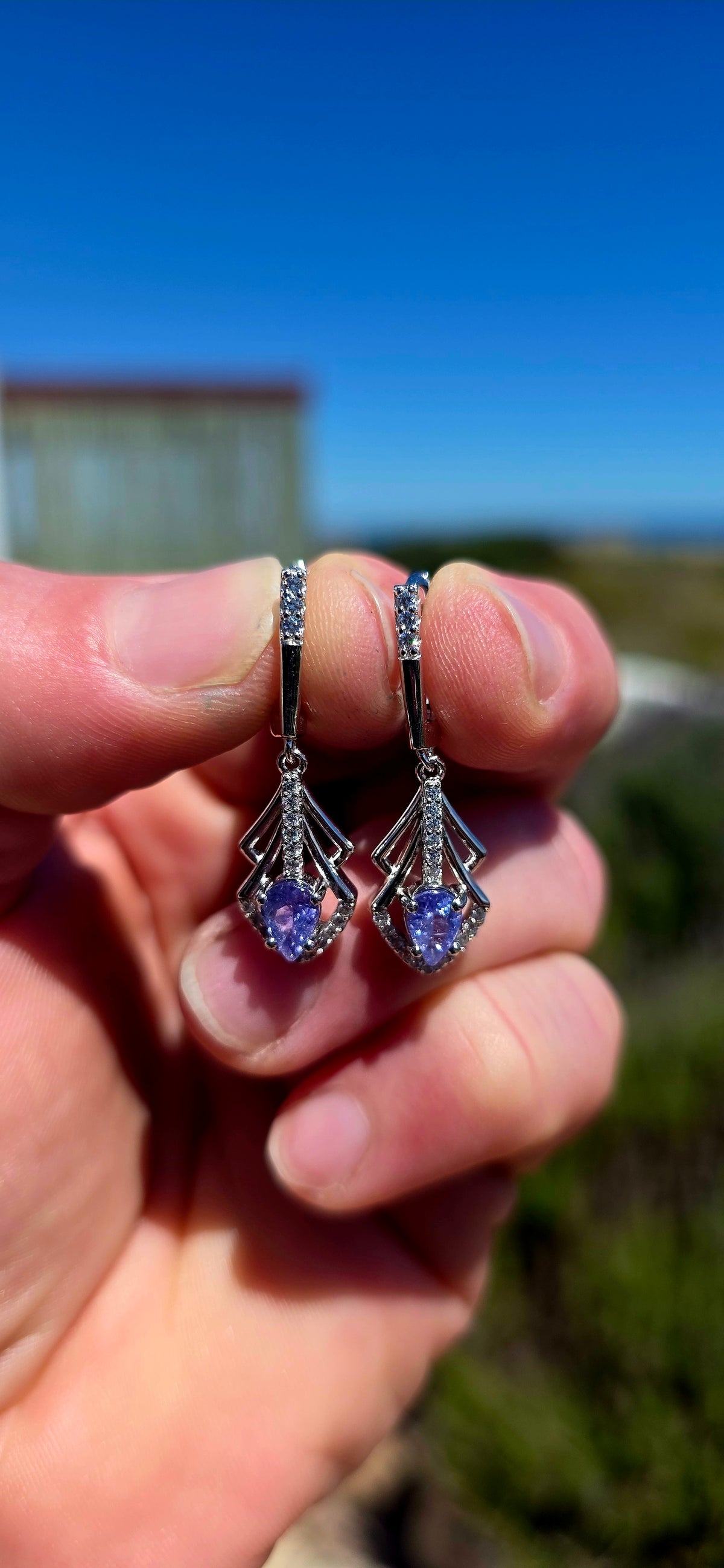 A beautifully elegant pair of Art Deco revival sterling silver drop earrings, featuring enchanting violet-blue tanzanites complemented by sparkling cubic zirconia gemstones!