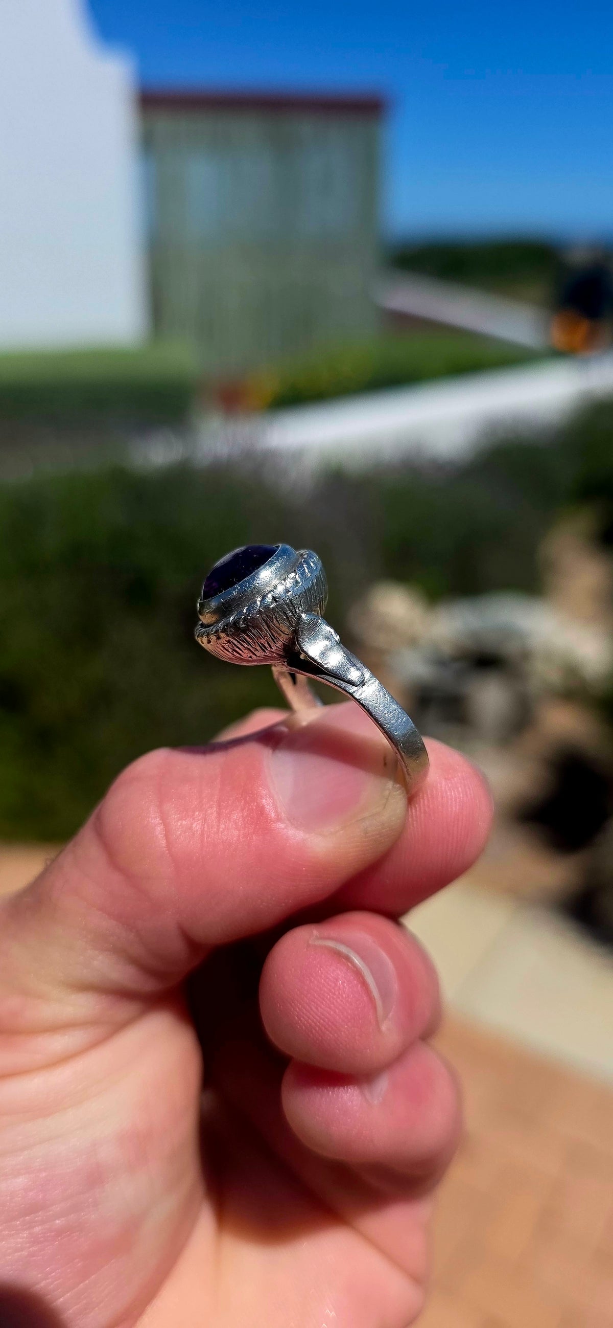 A striking handcrafted Kabwe sterling silver statement ring featuring a gorgeous, rounded purple amethyst cabochon, beautifully elevated within an elaborate sculptural silver setting.