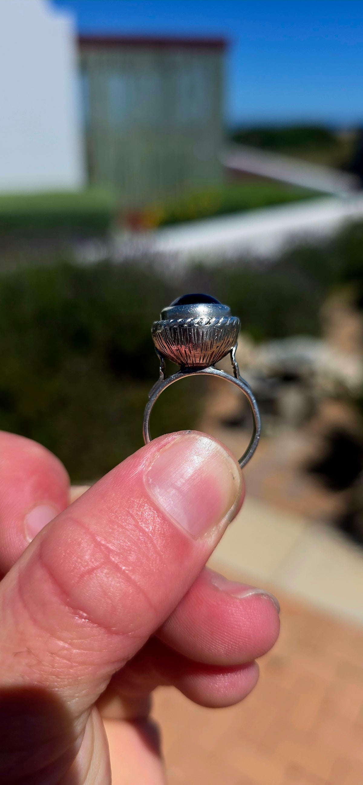 A striking handcrafted Kabwe sterling silver statement ring featuring a gorgeous, rounded purple amethyst cabochon, beautifully elevated within an elaborate sculptural silver setting.
