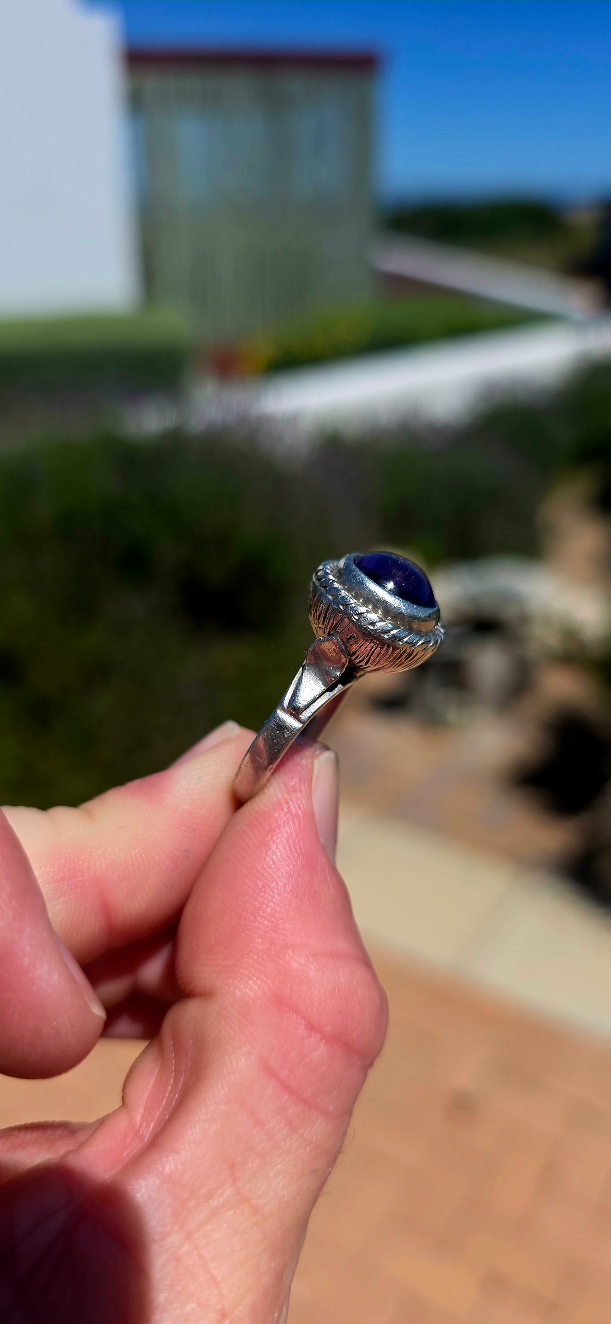 A striking handcrafted Kabwe sterling silver statement ring featuring a gorgeous, rounded purple amethyst cabochon, beautifully elevated within an elaborate sculptural silver setting.
