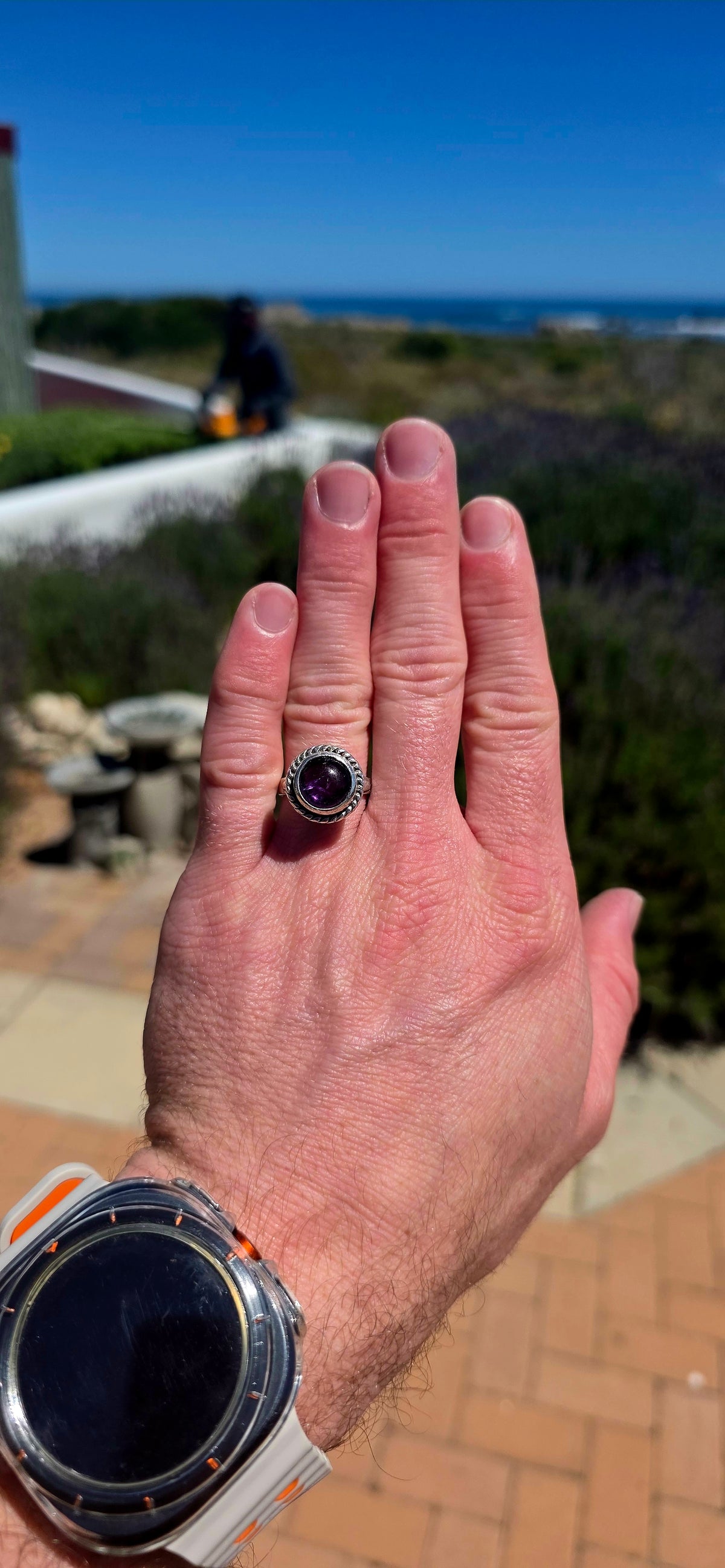 A striking handcrafted Kabwe sterling silver statement ring featuring a gorgeous, rounded purple amethyst cabochon, beautifully elevated within an elaborate sculptural silver setting.