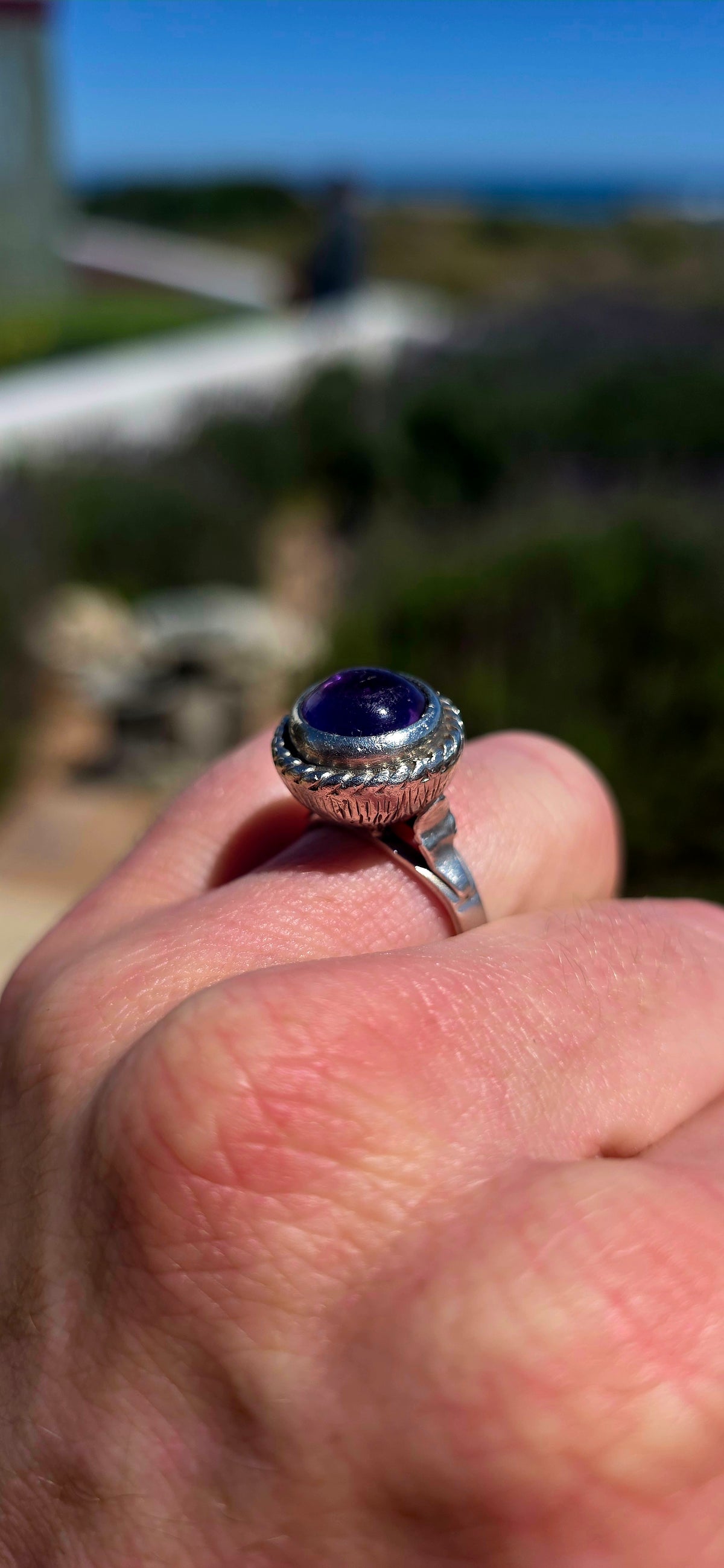 A striking handcrafted Kabwe sterling silver statement ring featuring a gorgeous, rounded purple amethyst cabochon, beautifully elevated within an elaborate sculptural silver setting.