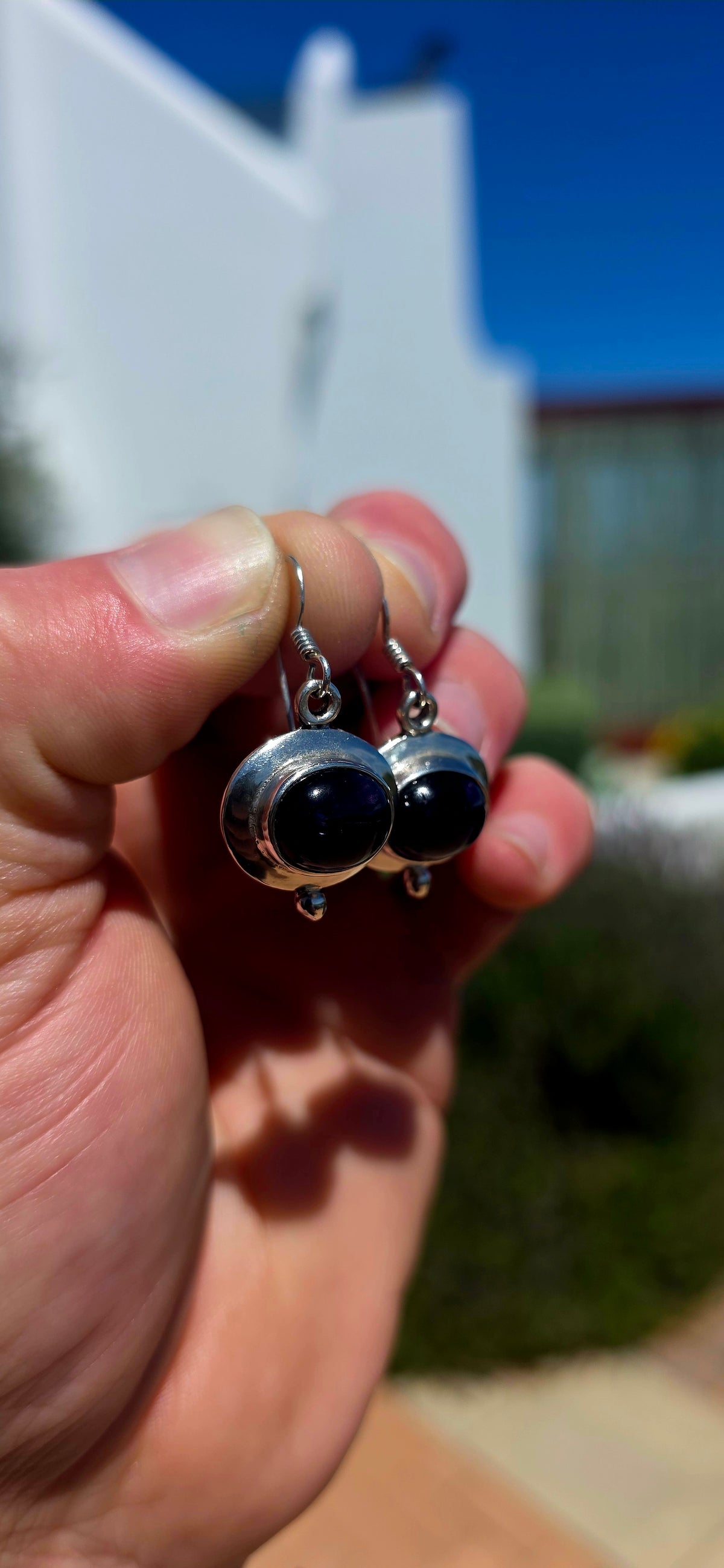 A beautiful pair of artisan-style sterling silver drop earrings featuring deep purple amethyst cabochons, beautifully complemented by sculptural silver settings.